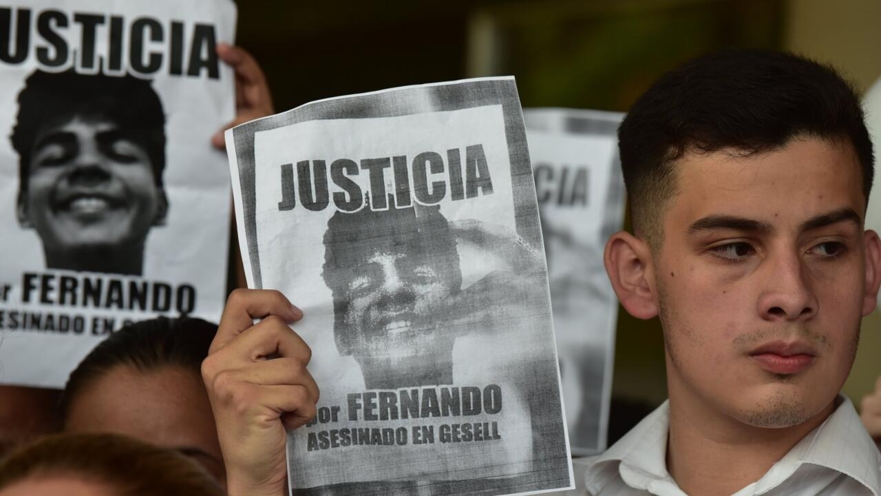 Un hombre sostiene un cartel con el retrato de Fernando Báez Sosa, asesinado a golpes hace tres años en Villa Gesell, Argentina, durante una protesta de estudiantes en Asunción en apoyo a la familia de Báez, de origen paraguayo, el 18 de enero de 2023. Foto: AFP.