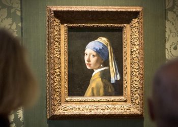Unos visitantes contemplan el cuadro 'La joven de la perla', de Johannes Vermeer, el 27 de octubre de 2022 en el museo Mauritshuis de La Haya. Foto: AFP.