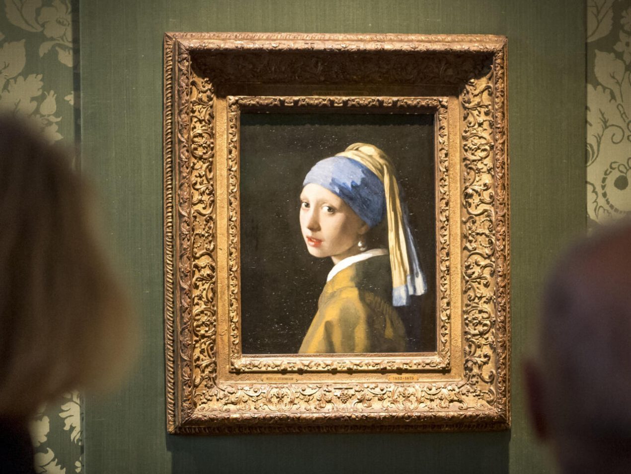 Unos visitantes contemplan el cuadro 'La joven de la perla', de Johannes Vermeer, el 27 de octubre de 2022 en el museo Mauritshuis de La Haya. Foto: AFP.