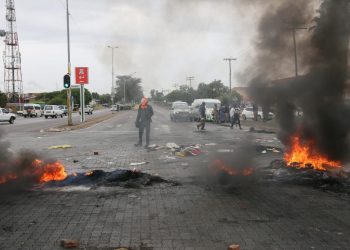 Un hombre monta una barricada con neumáticos durante una protesta contra los continuos cortes de agua y electricidad en Soshanguve, al norte de Pretoria, el 1 de febrero de 2023. Foto: AFP.